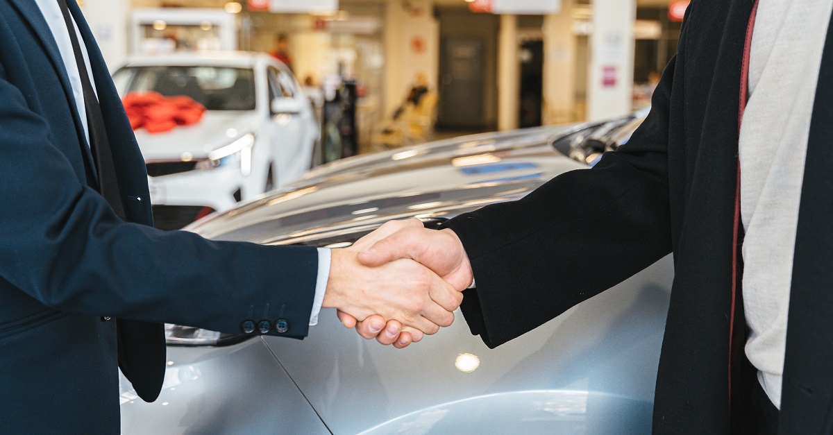 people shaking hands at a car dealership