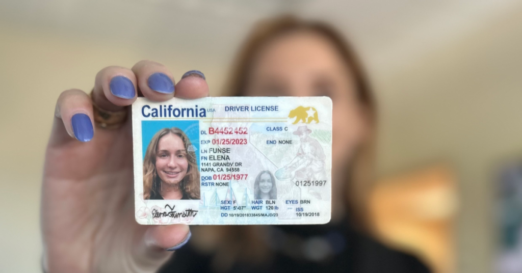 Woman holding fake ID in front of her face to get into a bar