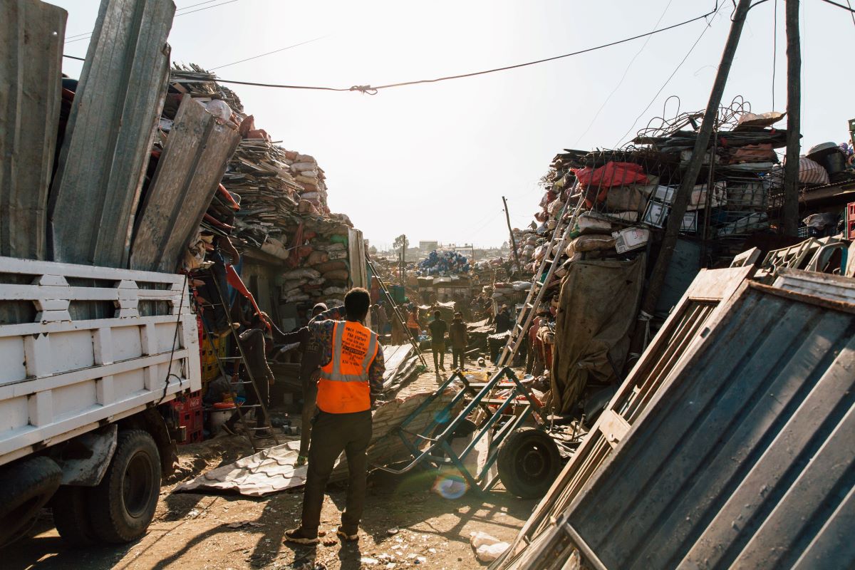 Individual in an orange vest at a scrap metal recycling facility