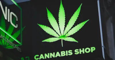 Black cannabis dispensary sign with a green marijuana leaf